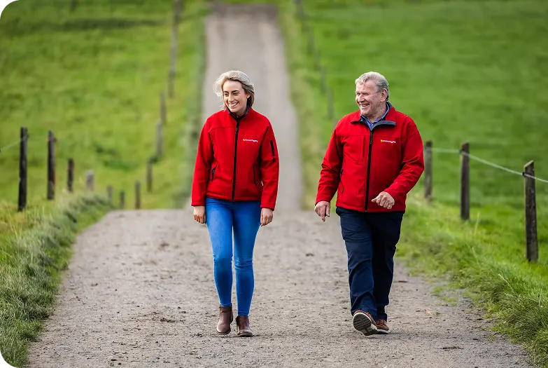 Man and woman in red Cormac Tagging jackets walking down a farm lane