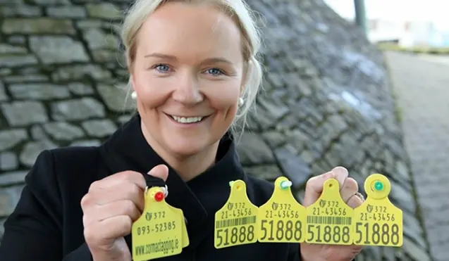 Smiling woman holding a set of yellow cattle ear tags